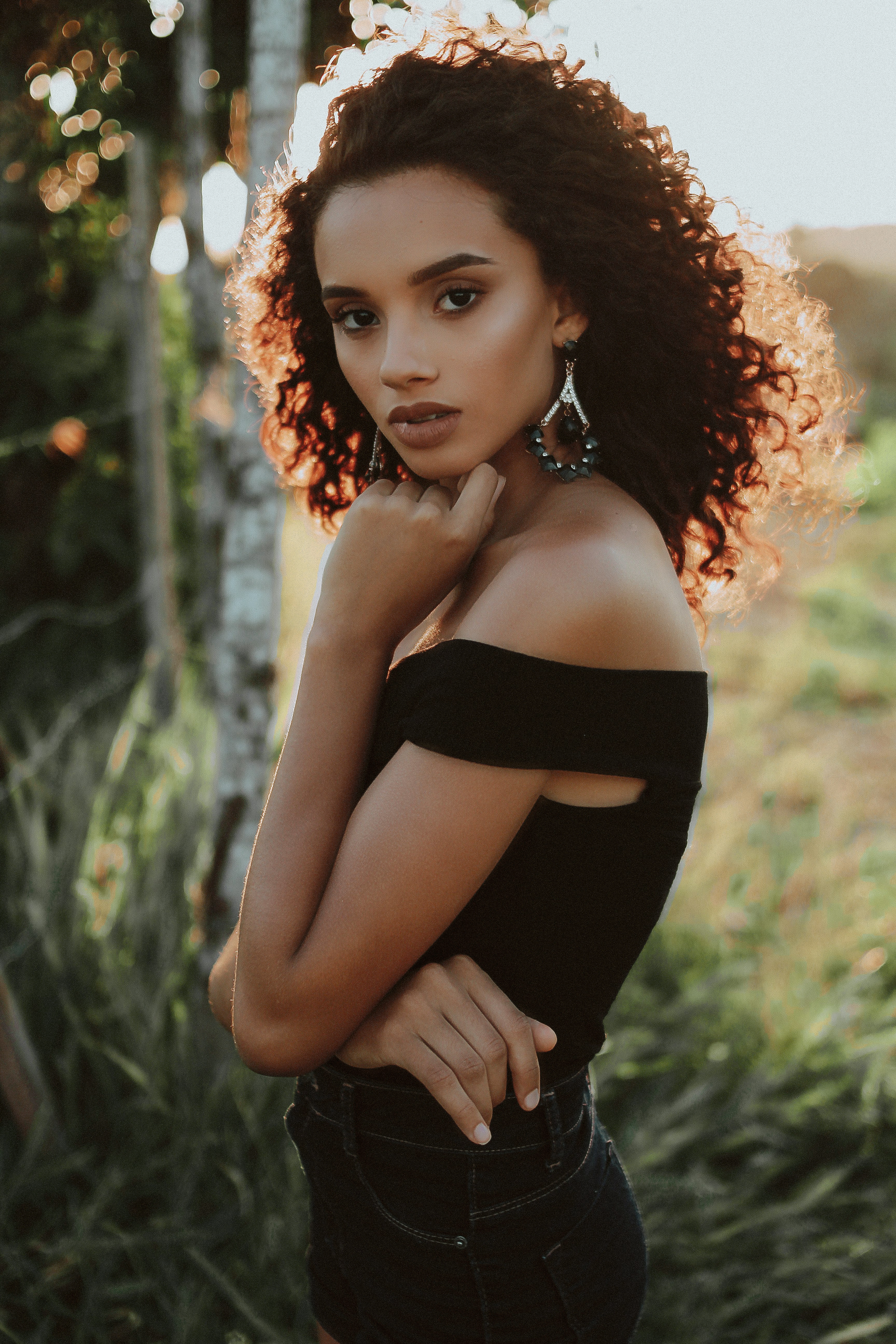 woman wearing black off-shoulder top with left hand under chin during daytime